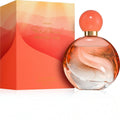 Marom Avon Far Away Endless Sun eau de parfum in a round glass bottle with a coral cap next to its sunset box