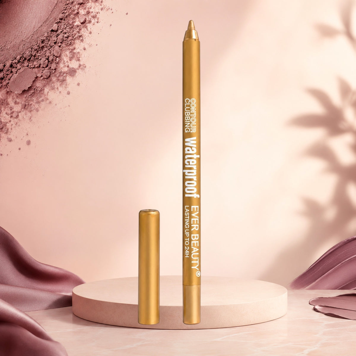 Marom EVER BEAUTY waterproof gold eye contour pencil standing on a circular pedestal with soft pink fabric background.