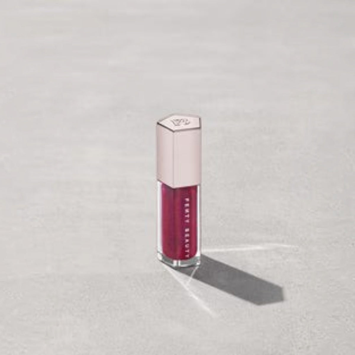 Marom Fenty Beauty Gloss Bomb Universal Lip Luminizer in a deep berry shade with a hexagonal cap
