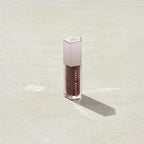 Marom Fenty Beauty Gloss Bomb Universal Lip Luminizer in a deep brown shade with a metallic cap