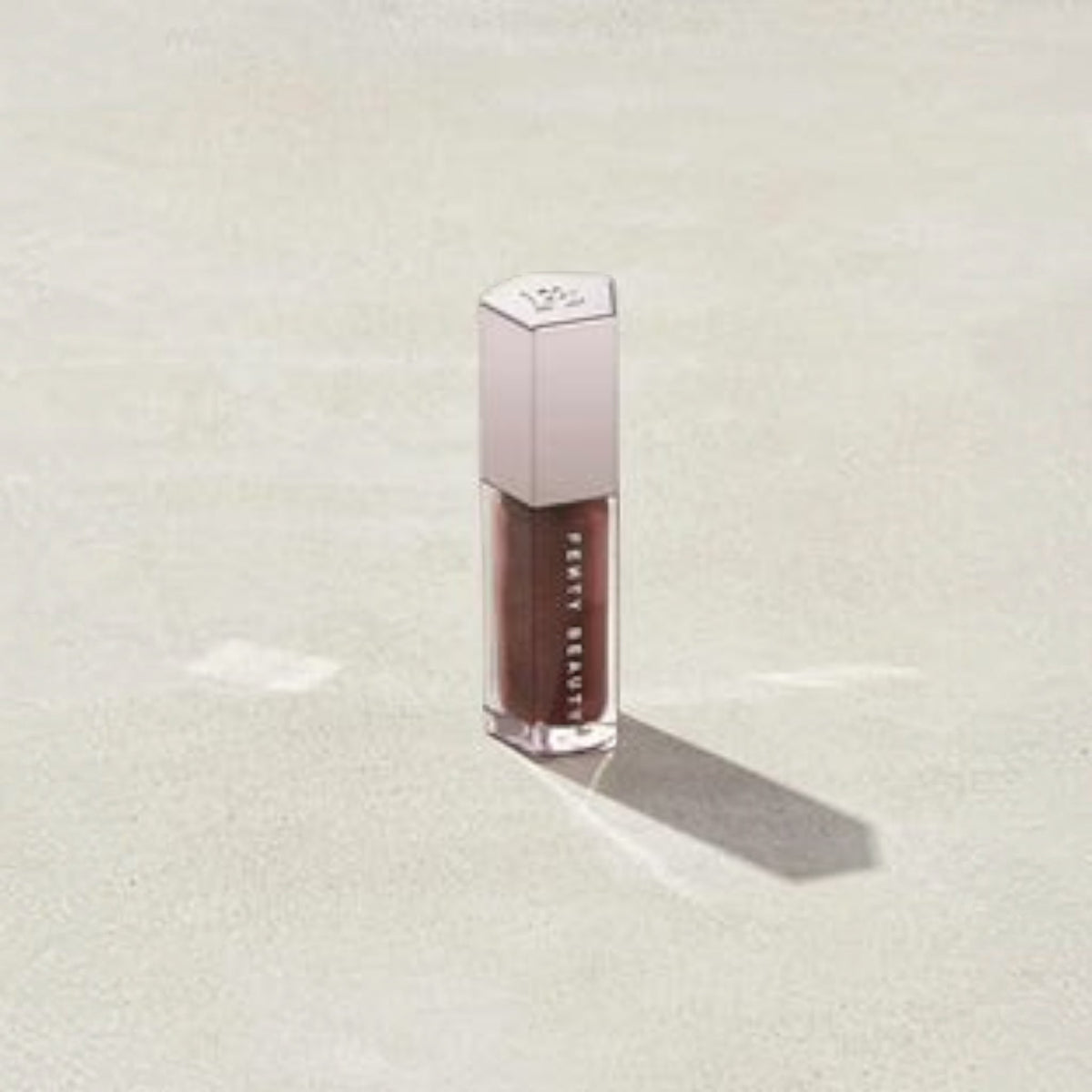 Marom Fenty Beauty Gloss Bomb Universal Lip Luminizer in a deep brown shade with a metallic cap