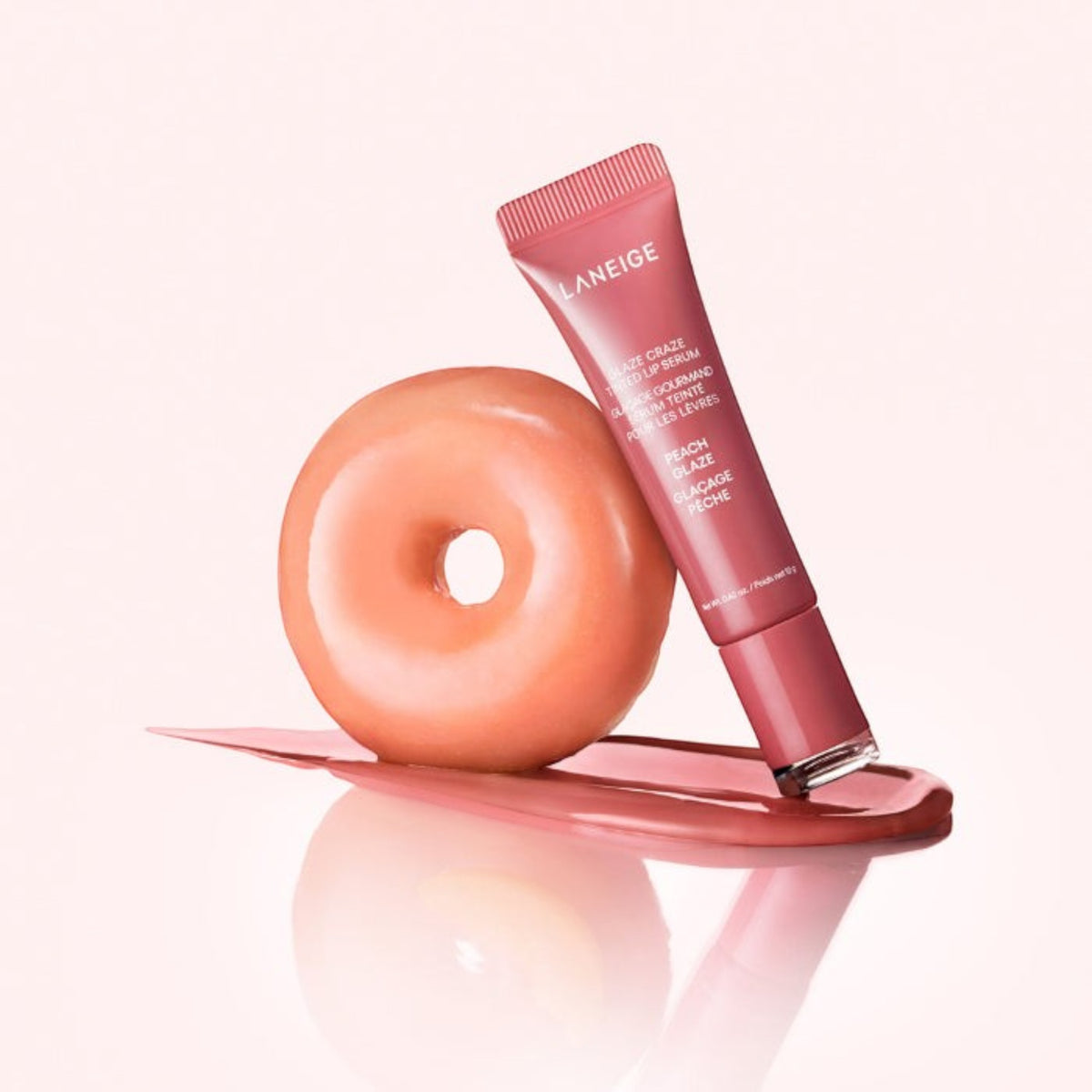 Marom LANEIGE Glaze Craze Tinted Lip Serum in Peach Glaze next to a glazed peach donut on a soft pink background.