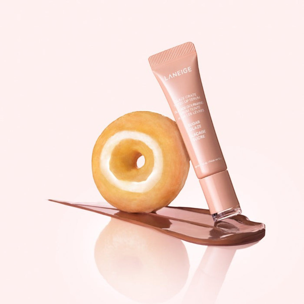 Marom LANEIGE Glaze Craze tinted lip serum tube with a donut and a glossy brown product swatch on a pink background