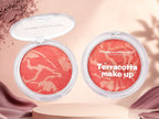 Marom MSYAHO terracotta makeup powder with a marbled coral and gold finish in a round clear compact case.