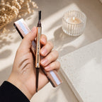 Marom ROSE BERRY dual-ended dark brown eyebrow pencil with spoolie brush held in hand showing swatch on skin