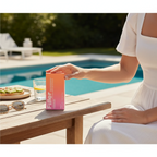 Marom Rose Berry Filler Comfy Smooth SPF 50 sunscreen box held by a woman on a wooden table by a sunny pool.